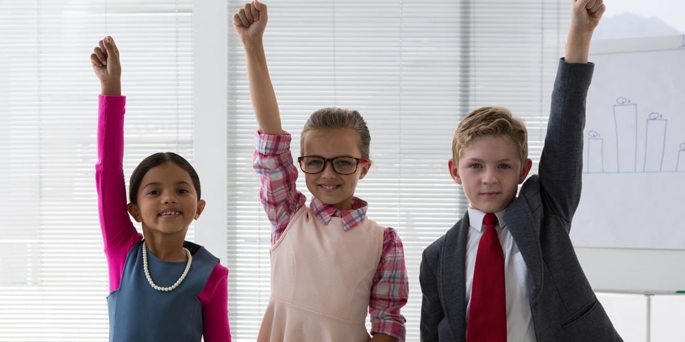 Kids as business executive smiling with their hands raised in the office at office